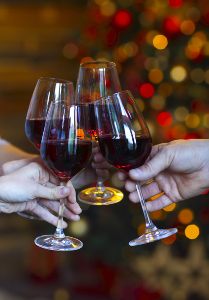 Clinking glasses of wine in hands on bright christmas lights bac - Photo, Image