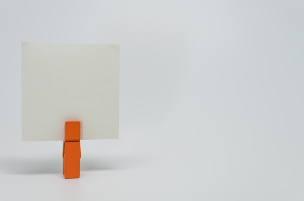 Кусок бумаги Memo, зажатый оранжевой деревянной обоймой с белым мешком
 - Фото, изображение