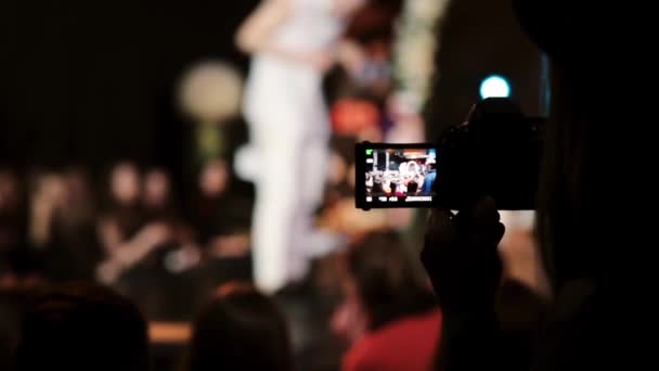 Closeup view of a girl holding camera and filming a dance. Blurred dancer on the background - Footage, Video