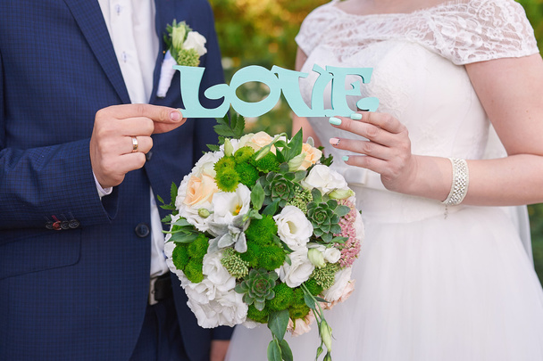 νύφης και του γαμπρού κρατώντας ξύλινη λέξη love - Φωτογραφία, εικόνα