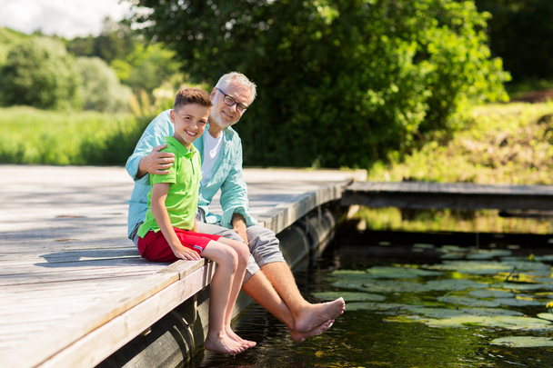 dziadek i wnuk siedzą na nabrzeżu rzeki - Zdjęcie, obraz