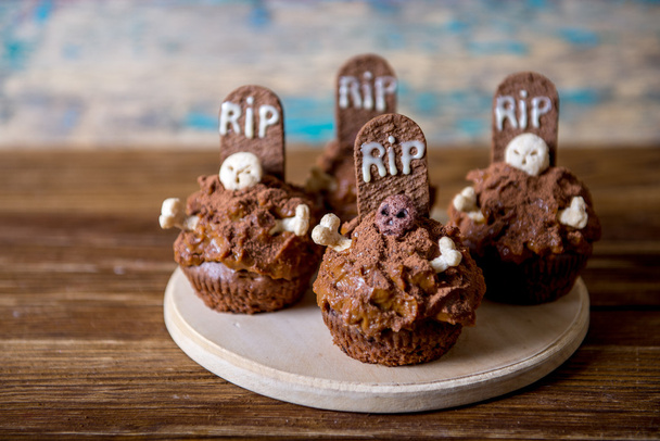 Cupcake di Halloween con topper per torta in pietra tombale e candela su un vecchio tavolo di legno
 - Foto, immagini