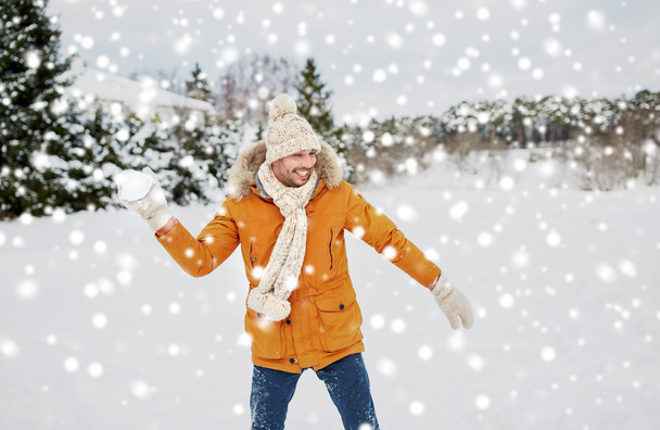 счастливый молодой человек играет в снежки зимой
 - Фото, изображение