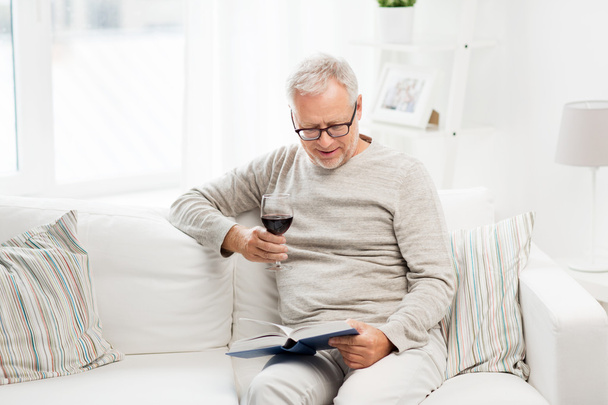 happy senior man drinking wine and reading book - Φωτογραφία, εικόνα