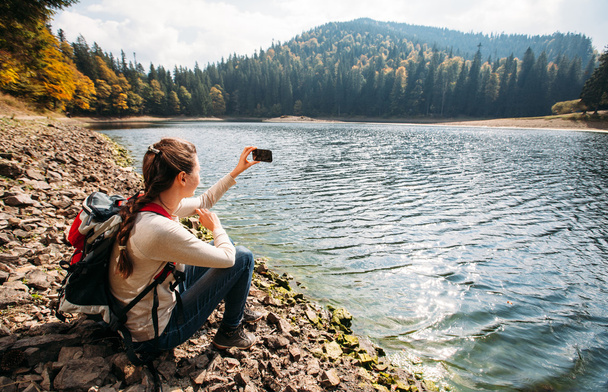 woman taking a picture with a smart phone while hiking in the na - Photo, Image