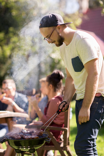 man cooking meat on barbecue grill at summer party - Photo, image