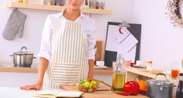 Усміхнена молода жінка стоїть на кухні
 - Фото, зображення