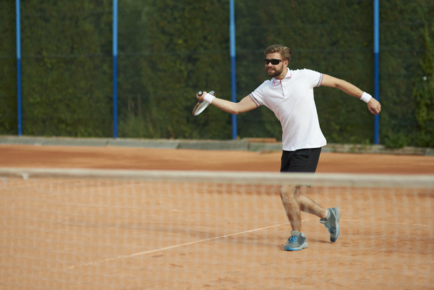 Мужчина играет в теннис в солнечный день
 - Фото, изображение