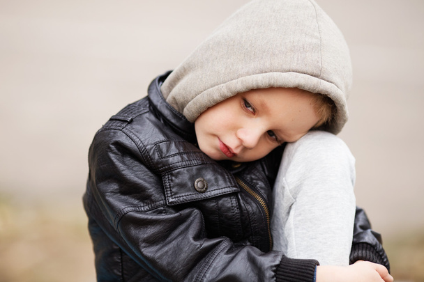 Porträt eines traurigen kleinen Jungen mit schwarzer Lederjacke und Kapuze - Foto, Bild