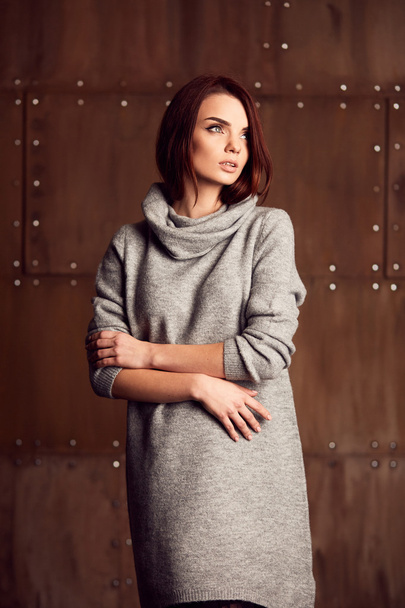 Young model posing in studio in grey dress - Foto, Imagen
