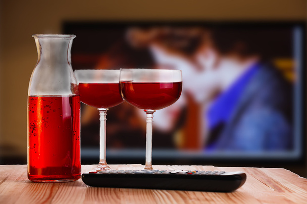 Due bicchieri e caraffa di vino con telecomando TV
. - Foto, immagini
