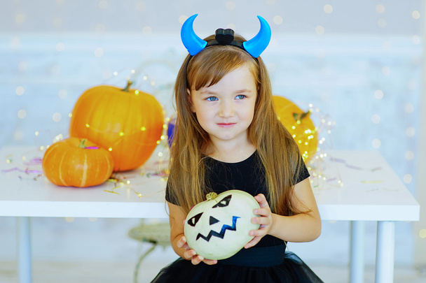 Little girl in demon costume playing with pumpkins - Фото, изображение