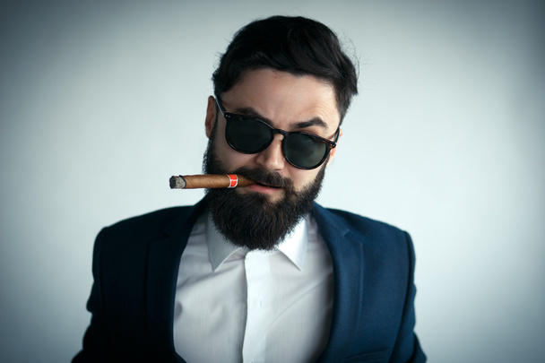 Portrait of male model making angry face and smoking a cigar - Foto, Imagen