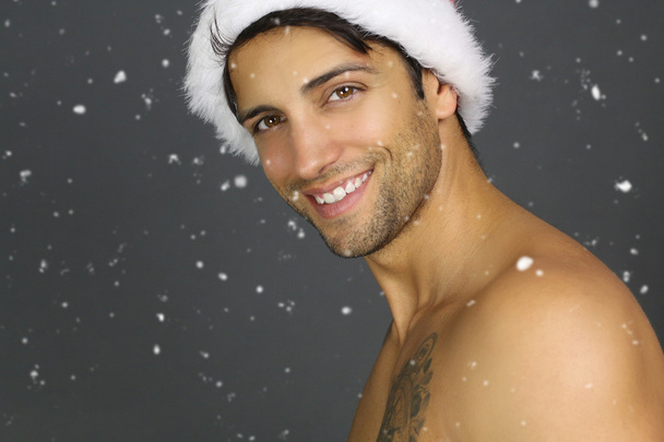 Homem atraente usando um chapéu de Papai Noel sorrindo
  - Foto, Imagem