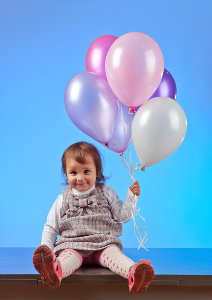  little girl with balloons on a blue background - Photo, Image