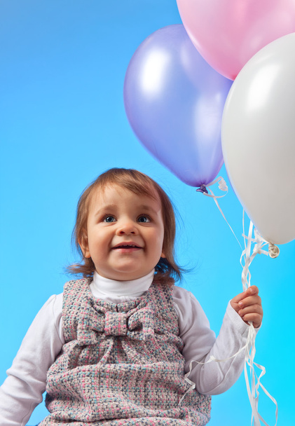  little girl with balloons on a blue background - Foto, imagen