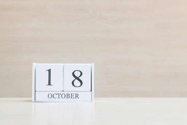 Closeup surface white wooden calendar with black 18 october word on blurred brown wood desk and wood wall textured background with copy space , view another more date in my portfolio - Photo, Image