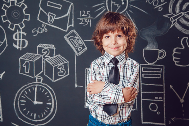 Маленький мальчик в качестве бизнесмена или учителя в рубашке и галстуке. Стоячие руки на темном фоне с фотографией бизнес-школы
 - Фото, изображение