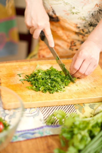Manos de mujer cortando cebollas frescas, eneldo, perejil en la cocina Enfoque en gree
 - Foto, imagen