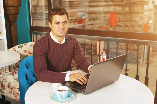 glücklicher junger Mann lächelt und arbeitet an seinem Laptop - Foto, Bild