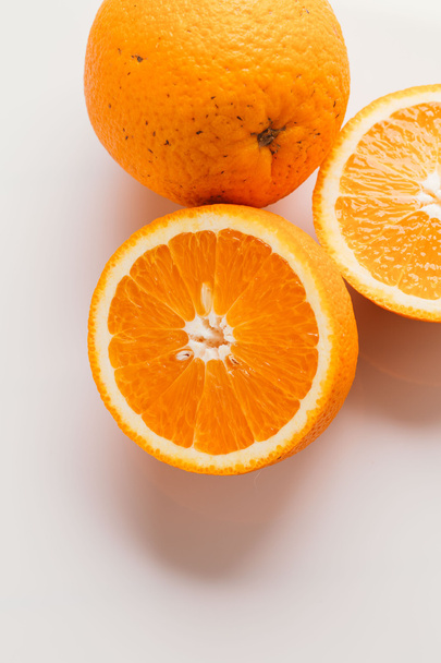 sliced orange halves and whole on a white background closeup - Valokuva, kuva