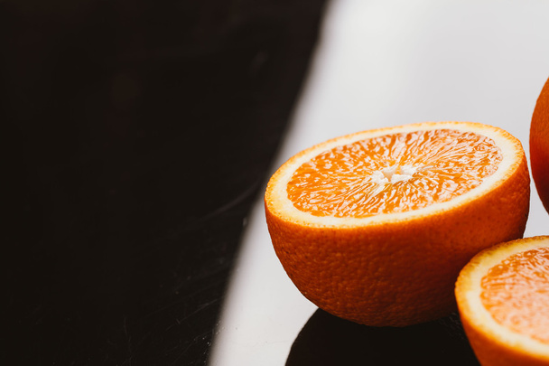 sliced orange halves and whole on a dark background closeup - Zdjęcie, obraz