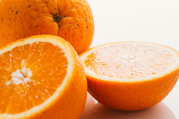 φέτες πορτοκαλιού στα ημίχρονα και ολόκληρη σε ένα λευκό φόντο closeup - Φωτογραφία, εικόνα