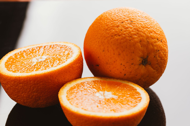 sliced orange halves and whole on a dark background closeup - Foto, imagen