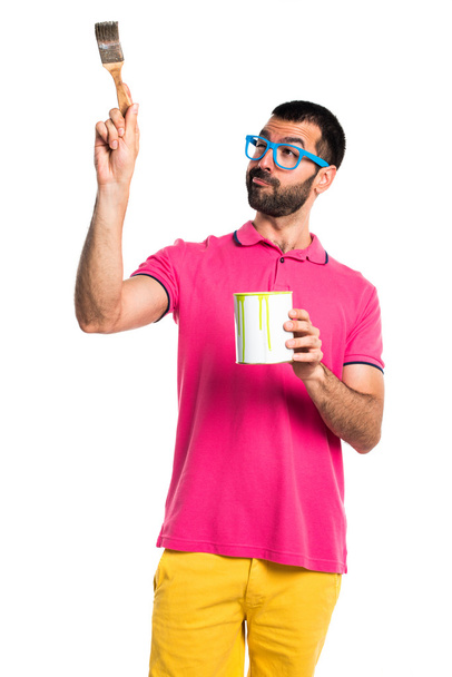 Человек в разноцветной одежде держит горшок с краской
 - Фото, изображение