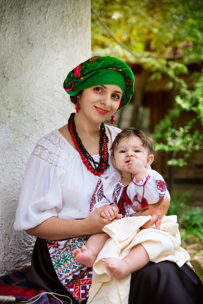 ウクライナのスーツを着たお母さんが赤ん坊の娘を保持します。 - 写真・画像