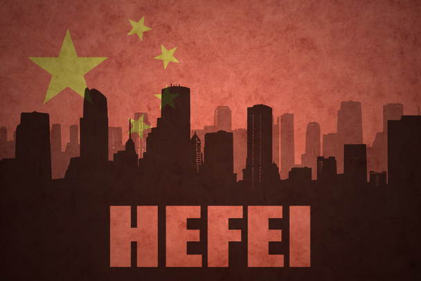 abstraktní silueta města s textem Hefei na starobylé čínské vlajkové pozadí - Fotografie, Obrázek