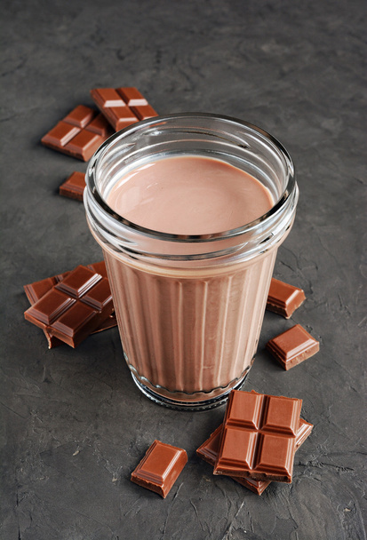Chocolate milk and pieces of chocolate bar and cocoa beans  - Фото, зображення