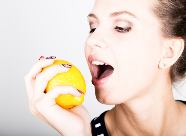 Happy smiling young woman holding fresh juicy lemons. Healthy eating, fruits and vegetables. - 写真・画像