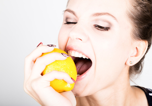 Happy smiling young woman holding fresh juicy lemons. Healthy eating, fruits and vegetables. - Фото, зображення