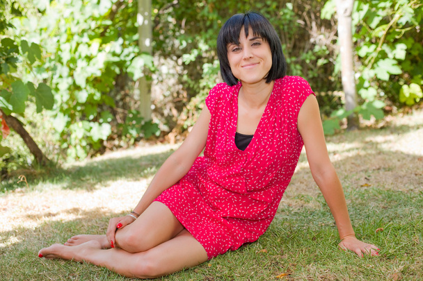 joven mujer casual posando sentada, sonriendo a la cámara, al aire libre
 - Foto, Imagen