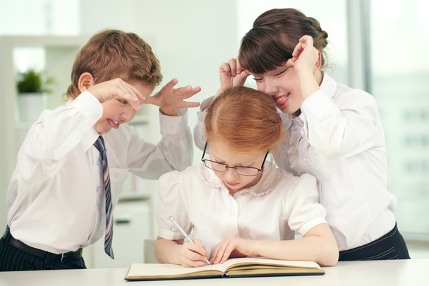 Schoolchildren making faces to a girl nerd - Photo, Image