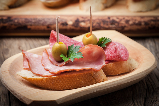 Tapas with sliced sausage, salami, olives and parsley. - Foto, afbeelding