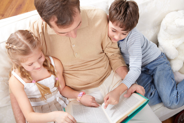 Isä lasten kanssa lukemassa kirjaa yhdessä
  - Valokuva, kuva