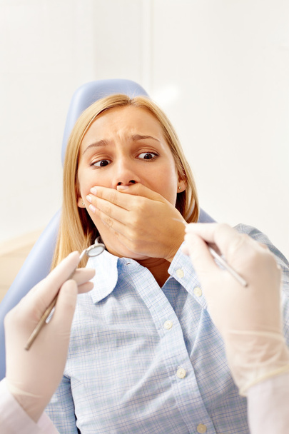 женщина в стоматологическом кресле закрывает рот
  - Фото, изображение
