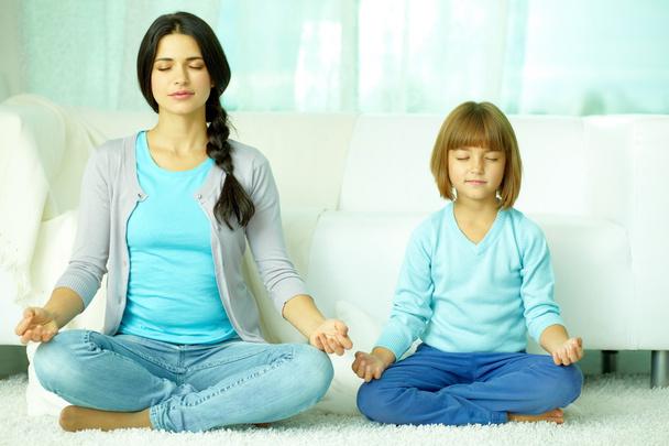 Mother with daughter meditating together - Foto, afbeelding
