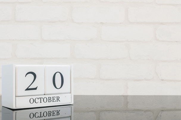 Gros plan calendrier en bois blanc avec mot noir 20 octobre sur table en verre noir et mur de briques blanches fond texturé avec espace de copie, mise au point sélective au calendrier
 - Photo, image