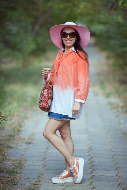 Beautiful young woman in elegant hat and sunglasses posing outdo - Фото, изображение