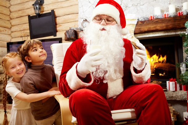 Weihnachtsmann isst Plätzchen mit Kindern - Foto, Bild