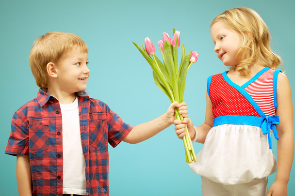 Junge schenkt Blumen an hübsches kleines Mädchen  - Foto, Bild