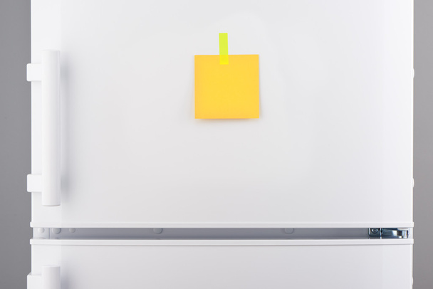 Yellow paper note attached with sticker on white refrigerator  - Zdjęcie, obraz