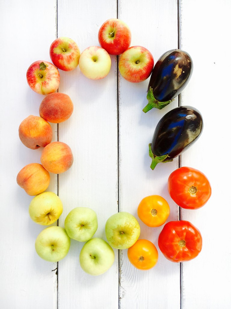 Разнообразие свежих летних фруктов и овощей - яблоки, персики, помидоры и баклажаны
.  - Фото, изображение