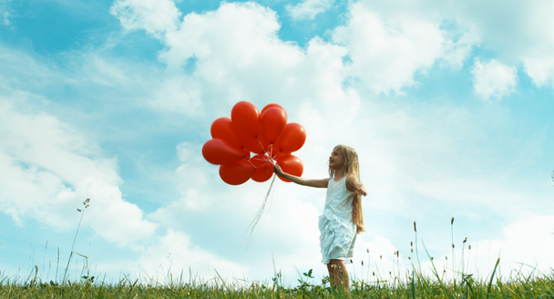 Girl with red balloons spinning at camera - Záběry, video