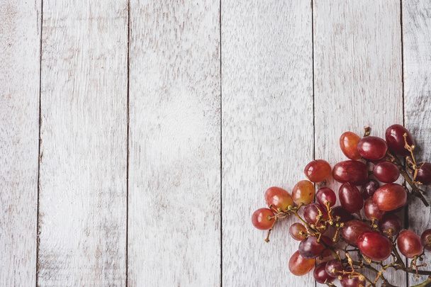 Vue du dessus des raisins rouges sur fond de table en bois blanc
. - Photo, image