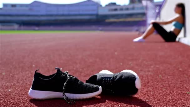 Desperate disappointed track runner athlete woman at a stadium, shoes in front, dolly - Footage, Video