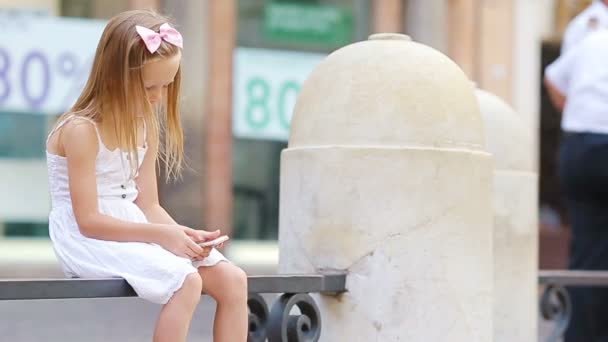 Adorable little girl with cellphone at warm day outdoors in european city near famous Fontana di Trevi - Footage, Video